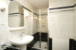 Une salle de bain équipée d’un lavabo, d’un miroir, d’une douche et d’un porte-serviettes.