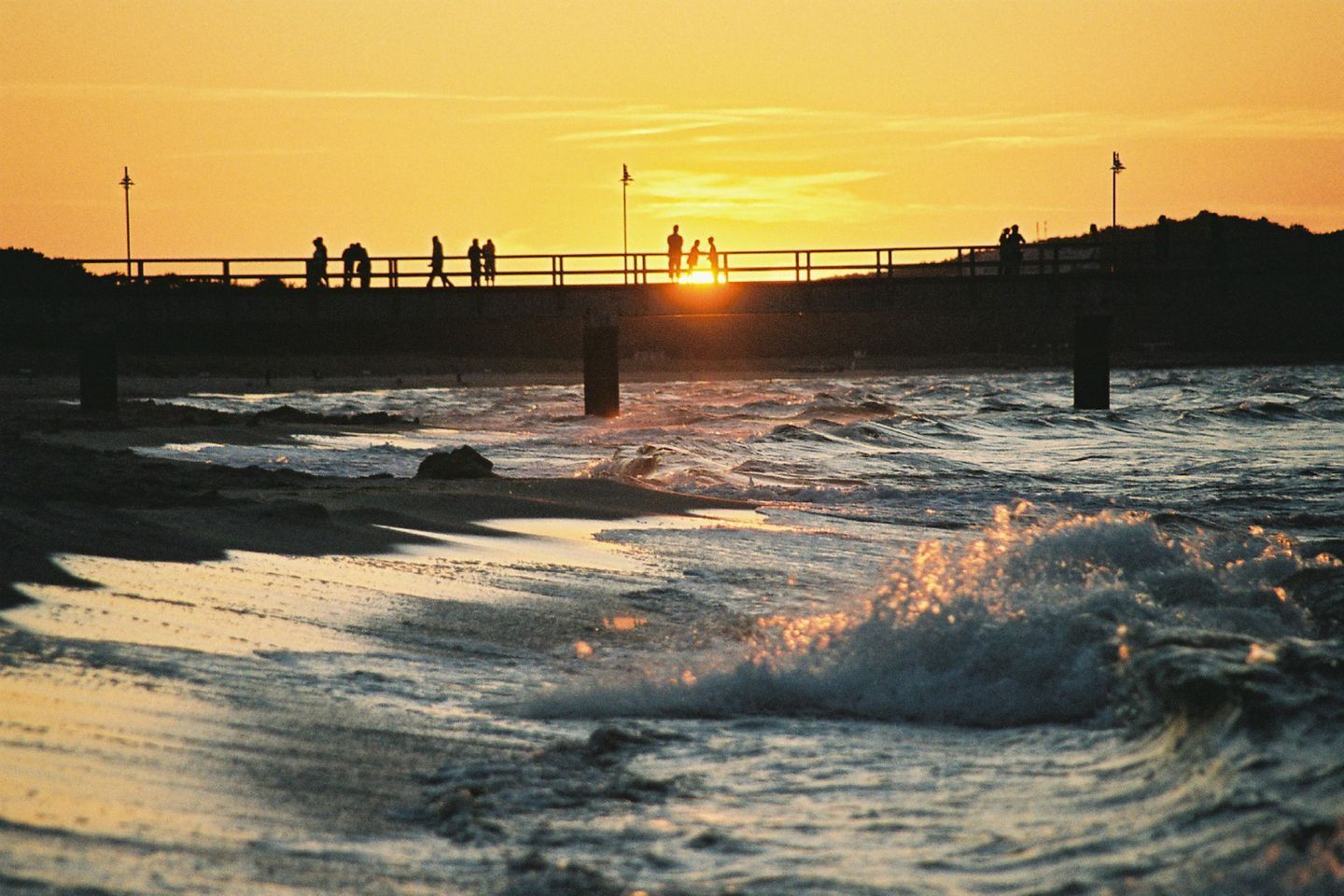 Atardecer sobre un puente con gente caminando.