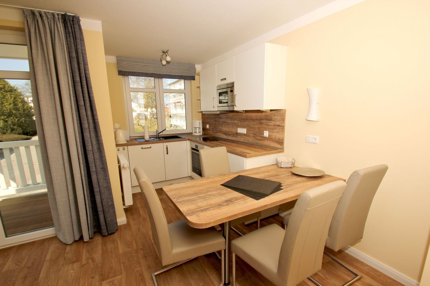 A modern kitchen with white cabinets, a wooden countertop, and a dining area with a wooden table and beige chairs.