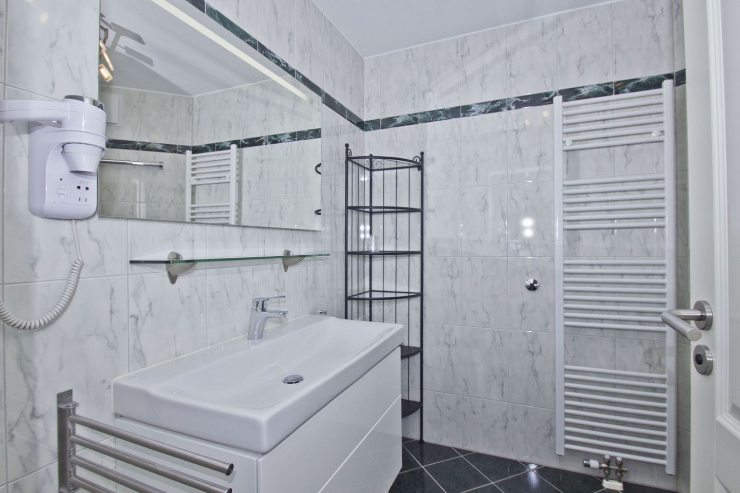 Ein modernes Badezimmer mit Waschbecken, Spiegel und Handtuchhalter.