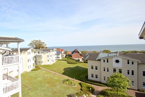 A residential area with a view of the sea, featuring houses with balconies and a well-maintained lawn. - With sea view and balcony, use of swimming pool and sauna - sea view apartment 27 - (Göhren)