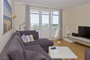 A modern living room with a grey sofa, a white coffee table, and a flat-screen TV.
