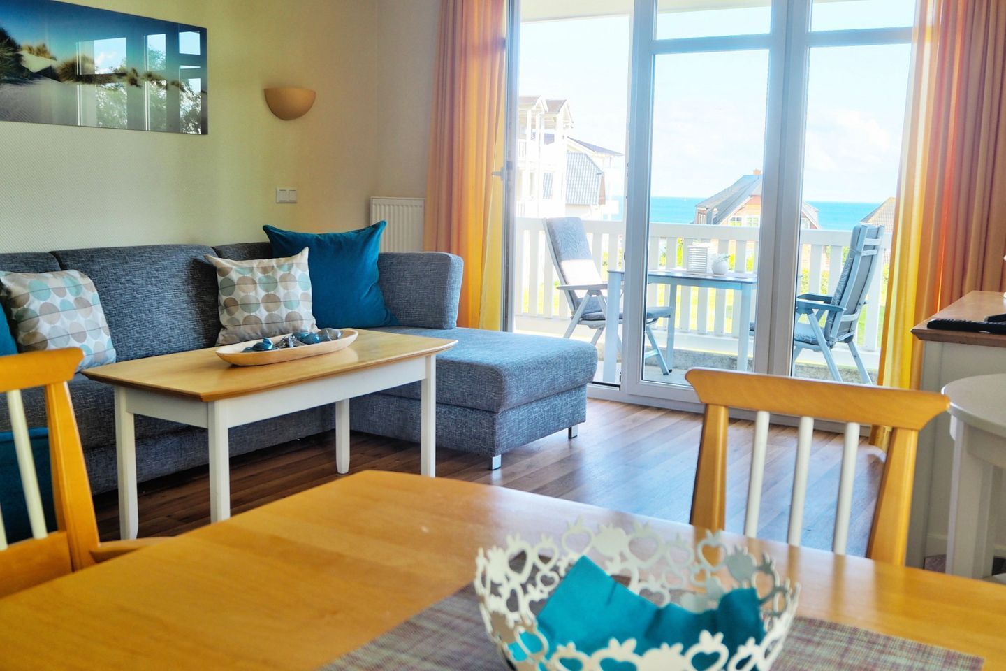 Un salon avec un canapé, une table en bois et une vue sur la mer grâce à de grandes fenêtres.