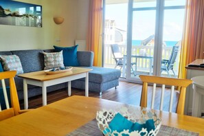 A living room with a sofa, a wooden table, and a view of the sea through large windows. - With a view of the sea and a balcony; access to the pool and sauna - Apartment 35 with a view of the sea - (Göhren)