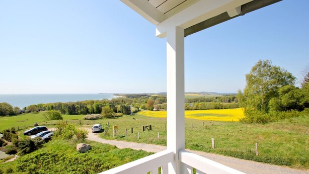 A balcony with a view of a coastal landscape, including fields and parked cars. - With sea view and balcony, use of swimming pool and sauna - Sea view apartment 18 - (Göhren)