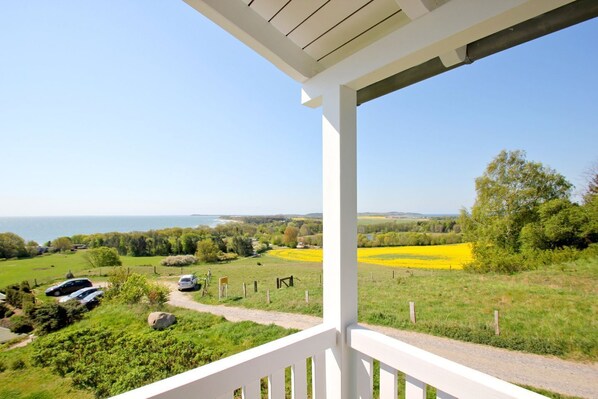 A balcony with a view of a coastal landscape, including fields and parked cars. - With sea view and balcony, use of swimming pool and sauna - Sea view apartment 18 - (Göhren)
