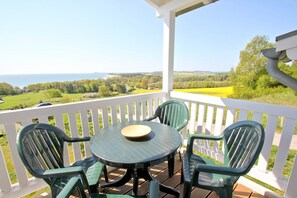 A covered patio with a table and chairs, overlooking a scenic landscape. - With a view of the sea and a balcony; access to the pool and sauna - Sea View Apartment 18 - (Göhren)