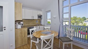 Una cocina moderna con armarios blancos, encimera de madera y un comedor con una mesa redonda y sillas blancas.