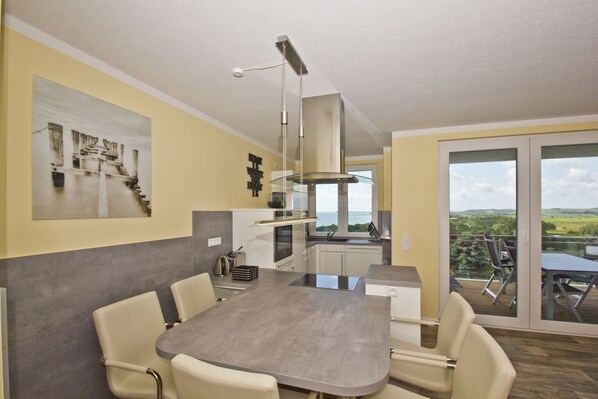 A modern kitchen with a dining area, large windows, and a view of the countryside.