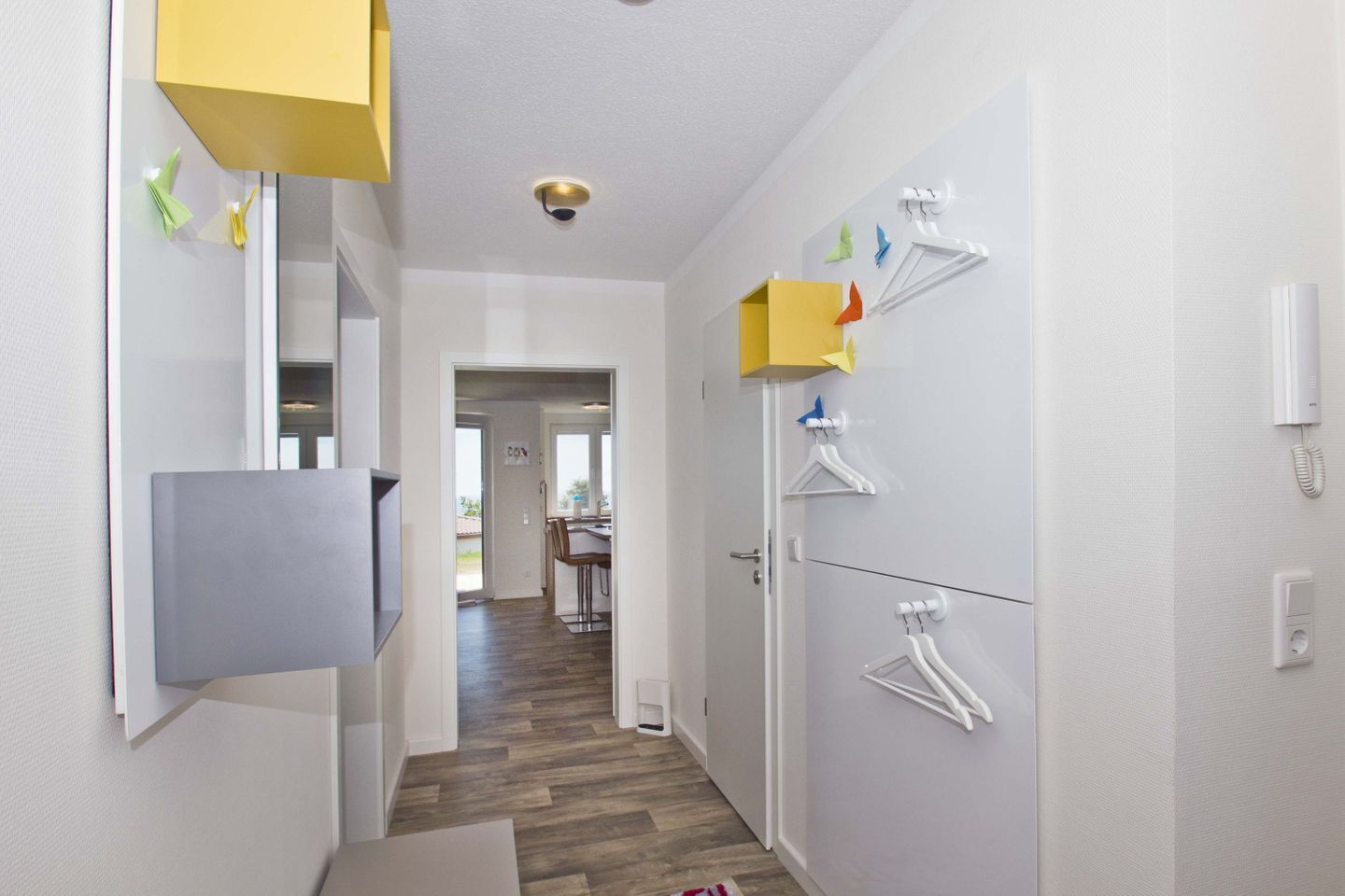 A narrow hallway with a wooden floor, a grey cabinet, and a yellow storage unit.