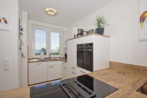 Et moderne køkken med hvide skabe, en indbygget ovn og et vindue med udsigt.