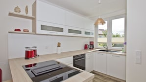 A modern kitchen with white cabinets, a built-in stove, and a window with a view of the outside.