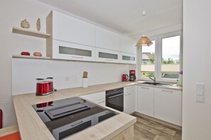 Una cocina moderna con armarios blancos, estufa integrada y ventana con vistas al exterior.