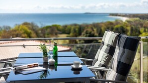 Un balcon avec une table, des chaises et une vue sur la mer.