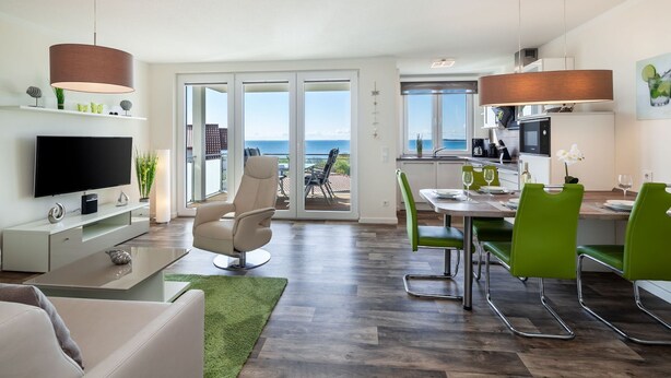 Un salon moderne avec un téléviseur à écran plat, un canapé confortable et un tapis vert.