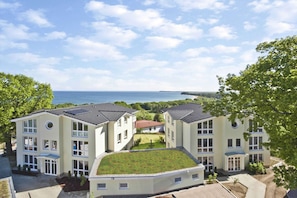 A modern building with multiple floors, a flat roof, and a view of the sea. - With sea view and balcony, use of swimming pool and sauna - sea view apartment 70 - (Göhren)