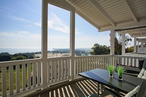 A covered outdoor area with a table and chairs, overlooking a scenic landscape.