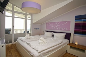 Un dormitorio con una cama grande, un ventilador de techo, una ventana con persianas y una pared con una cita motivacional.