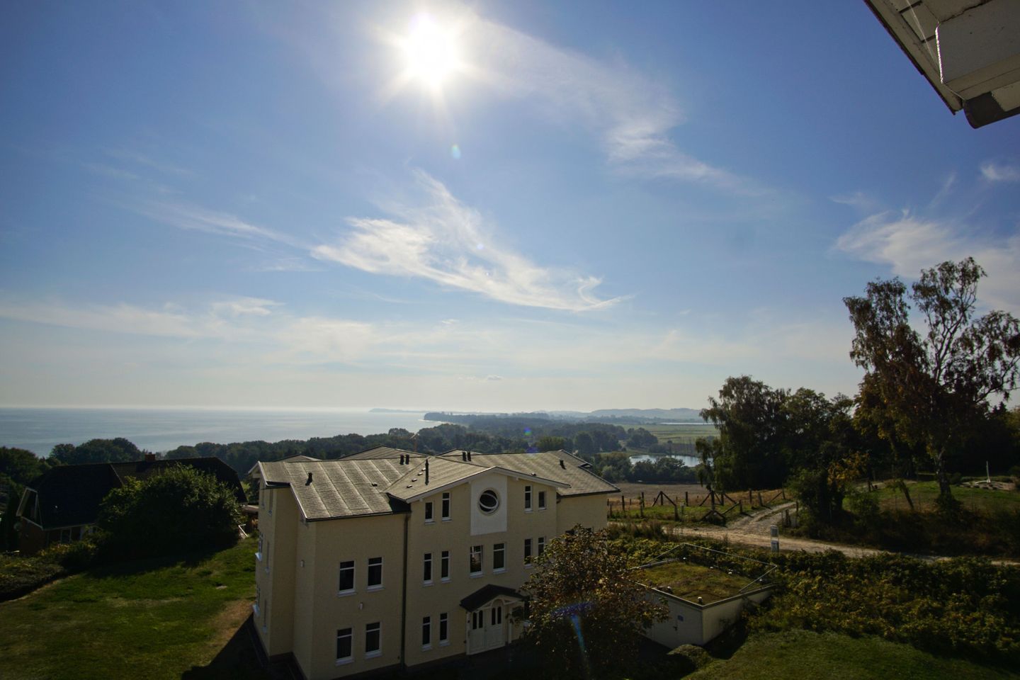 Un bâtiment doté d’un toit plat, de nombreuses fenêtres et offrant une vue sur la mer et les collines lointaines.