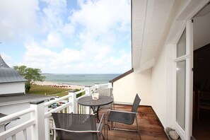 Ein Balkon mit Tisch und Stühlen mit Blick auf Strand und Steg.