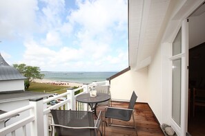 Ein Balkon mit Tisch und Stühlen mit Blick auf Strand und Steg.