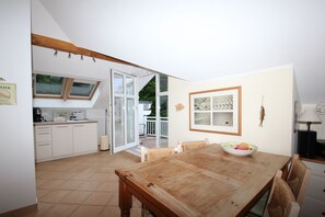 Eine Küche mit weißen Schränken und ein Essbereich mit einem Holztisch und Stühlen.