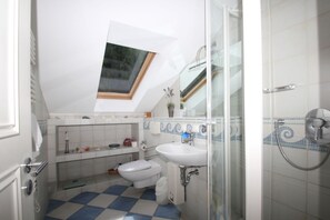 Ein Badezimmer mit Dachfenster, Dusche und einem Schachbrettmuster-Boden.