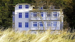 Un edificio de varios pisos con fachada simétrica, ventanas amplias y techo plano.