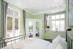 A hotel room with a bed, a window with curtains, a radiator, and a view of the outside.