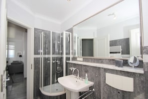 A modern bathroom with a glass-enclosed shower, a white sink, and a large mirror.