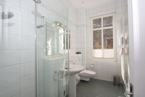 Une salle de bain moderne avec une douche à parois de verre, un lavabo et des toilettes.