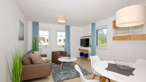 Ein modernes Wohnzimmer mit einer Couch, einem runden Couchtisch und einem Essbereich mit Tisch und Stühlen.