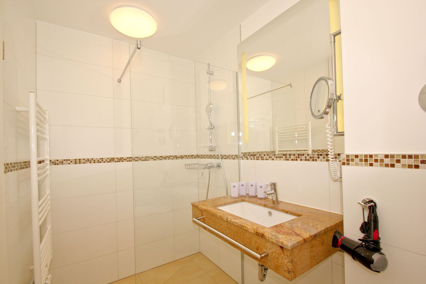 A modern bathroom with a glass-enclosed shower, a marble sink, and a large mirror.
