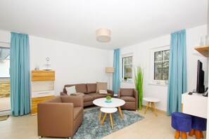 A modern living room with a sofa set, a coffee table, a side table, and a TV stand. - Beachfront vacation rental with a terrace, access to the pool and sauna - Rex Rugia H-1010 - (Göhren)