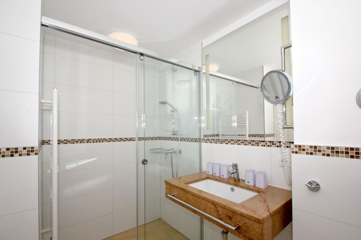 Une salle de bain moderne avec une douche à parois de verre, un lavabo avec un meuble-vasque et un miroir.