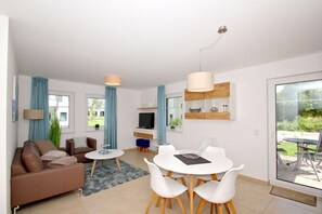 Un salon moderne comprenant un canapé, un téléviseur, une table à manger et des chaises.