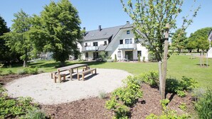 A two-story house with a balcony, surrounded by a well-maintained lawn and a small garden area with a wooden bench. - Beachfront vacation rental with a terrace, access to the pool and sauna - Rex Rugia H-1010 - (Göhren)