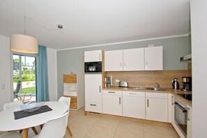 A modern kitchen with white cabinets, a wooden countertop, a sink, and a coffee maker. - Beachfront vacation rental with a terrace, access to the pool and sauna - Rex Rugia - Rex (Göhren)