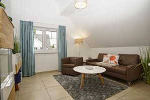 Een moderne woonkamer met een bruine bank, een ronde salontafel en een lamp.