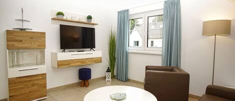 Ein modernes Wohnzimmer mit Fernseher, Sofa und Couchtisch.
