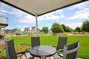An outdoor patio with a table and chairs, a covered area, and a view of houses and trees in the background. - Beachfront vacation rental with a terrace, access to the pool and sauna - Rex Rugia H-1010 - (Göhren)
