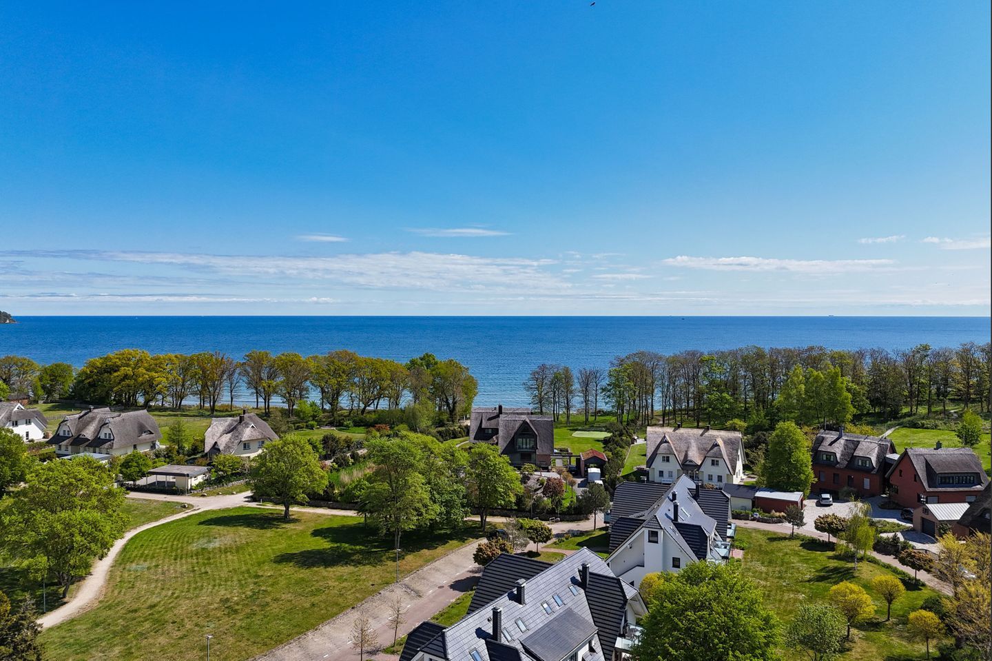 Un quartier résidentiel situé sur la côte, avec des maisons, un ciel dégagé et une vue sur la mer.