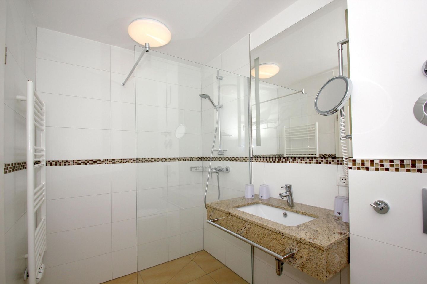 A modern bathroom with a glass-enclosed shower, a vanity with a sink, and a mirror.