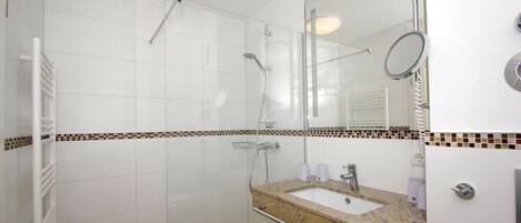 A modern bathroom with a glass-enclosed shower, a vanity with a sink, and a mirror.
