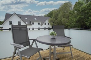 A rooftop terrace with a round table, two chairs, and a potted plant. - Beachfront vacation rental with a balcony, access to the pool and sauna - Rex Rugia H-1010 - (Göhren)