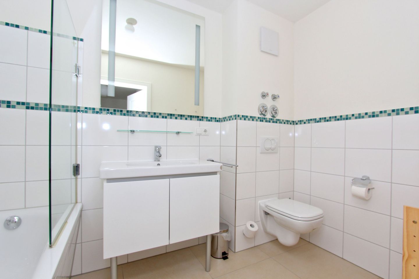 A bathroom with a glass shower enclosure, a white sink with a mirror above, and a toilet.