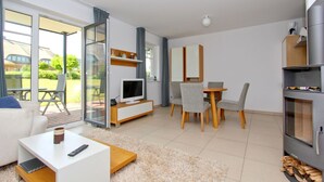A modern living room with a TV, sofa, coffee table, and dining area with chairs.