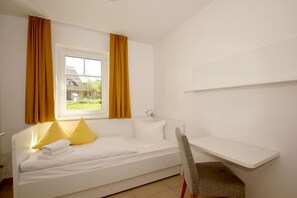 A small, single-bed room with a window, a chair, and a bedside table. - Beachfront vacation rental with a terrace, access to the pool and sauna - Rex Rugia - Rex (Göhren)
