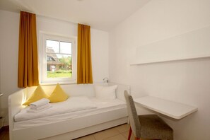 A single-bed room with a window, a chair, and a small white shelf. - Beachfront vacation rental with a terrace, access to the pool and sauna - Rex Rugia H-1010 - (Göhren)