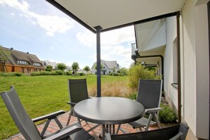 A patio with a round table and four chairs, a covered area, and a view of a residential neighborhood. - Beachfront vacation rental with a terrace, access to the pool and sauna - Rex Rugia H-1010 - (Göhren)
